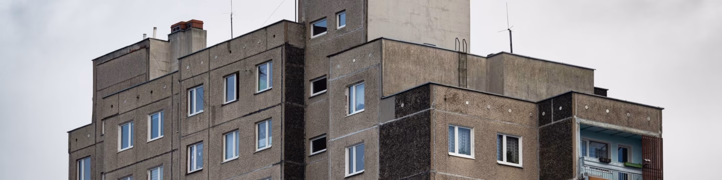 Side view of a brown tower block against a cloudy grey sky.