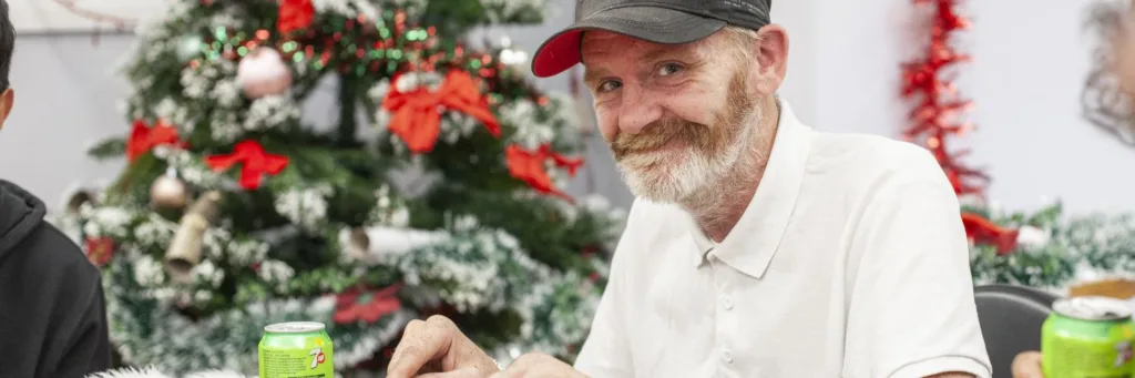 Man smiling with a Christmas tree behind him